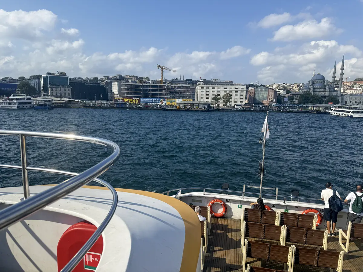 Open deck of an Istanbul ferry crossing to Kadıköy, with the Eminönü waterfront and New Mosque behind