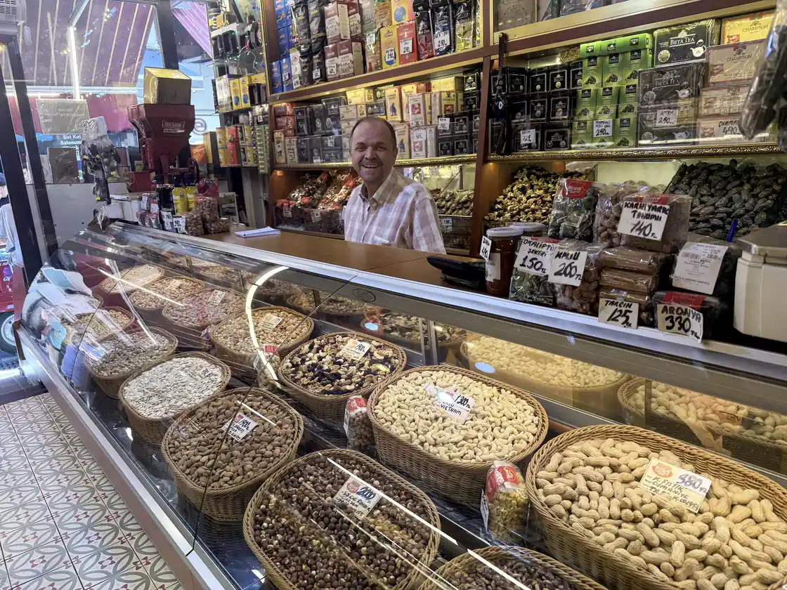 Delicatessen owner behind a counter of Turkish cheeses, olives and dried goods in Kadıköy Market