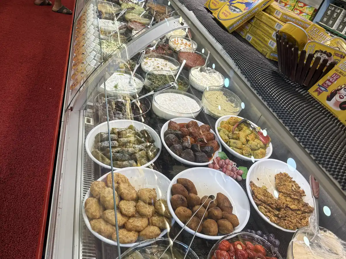 Glass counter of colourful Turkish meze — stuffed vine leaves, patties, yogurt dips and salads — at a delicatessen in Kadıköy Market, Istanbul