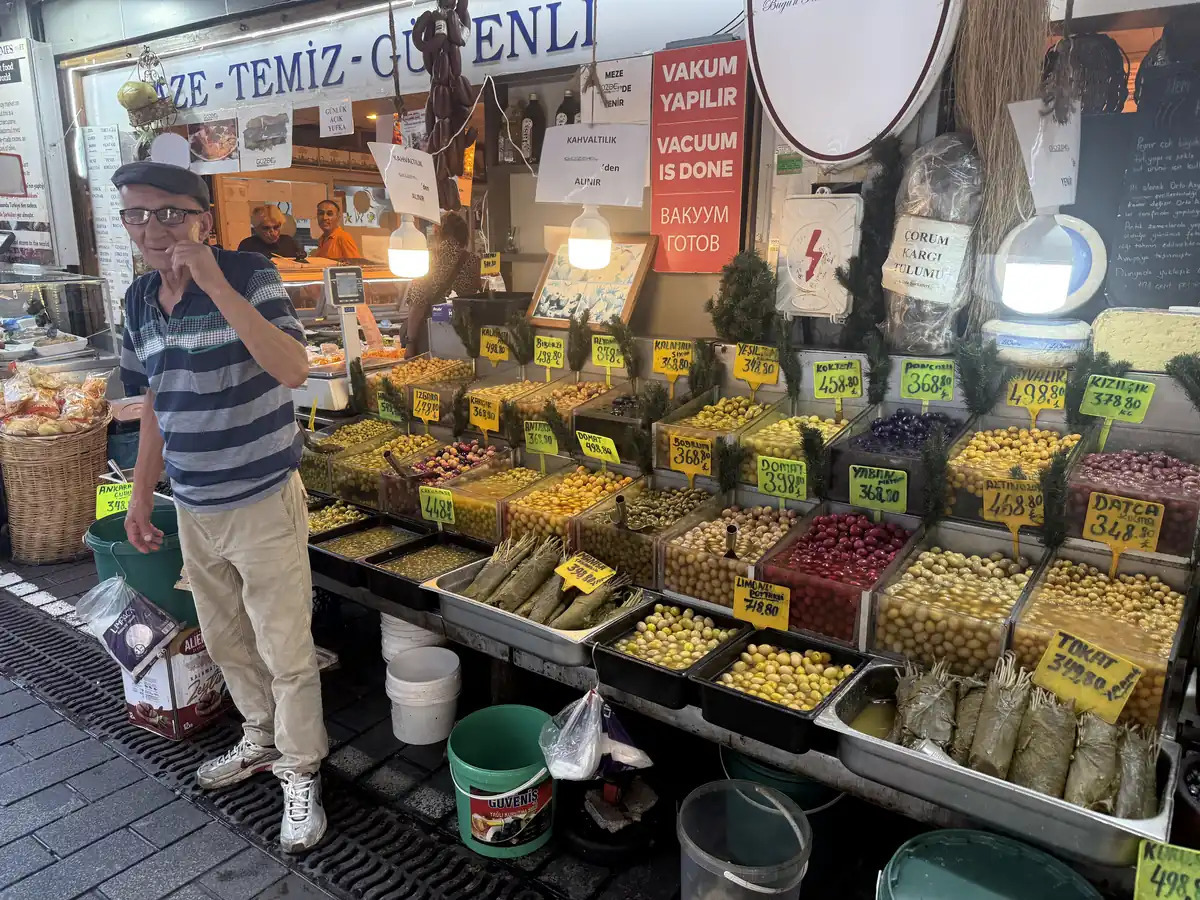 Vendor offering olives at a traditional stall in Kadıköy Market — olives and olive oil are the foundation of the cold meze table