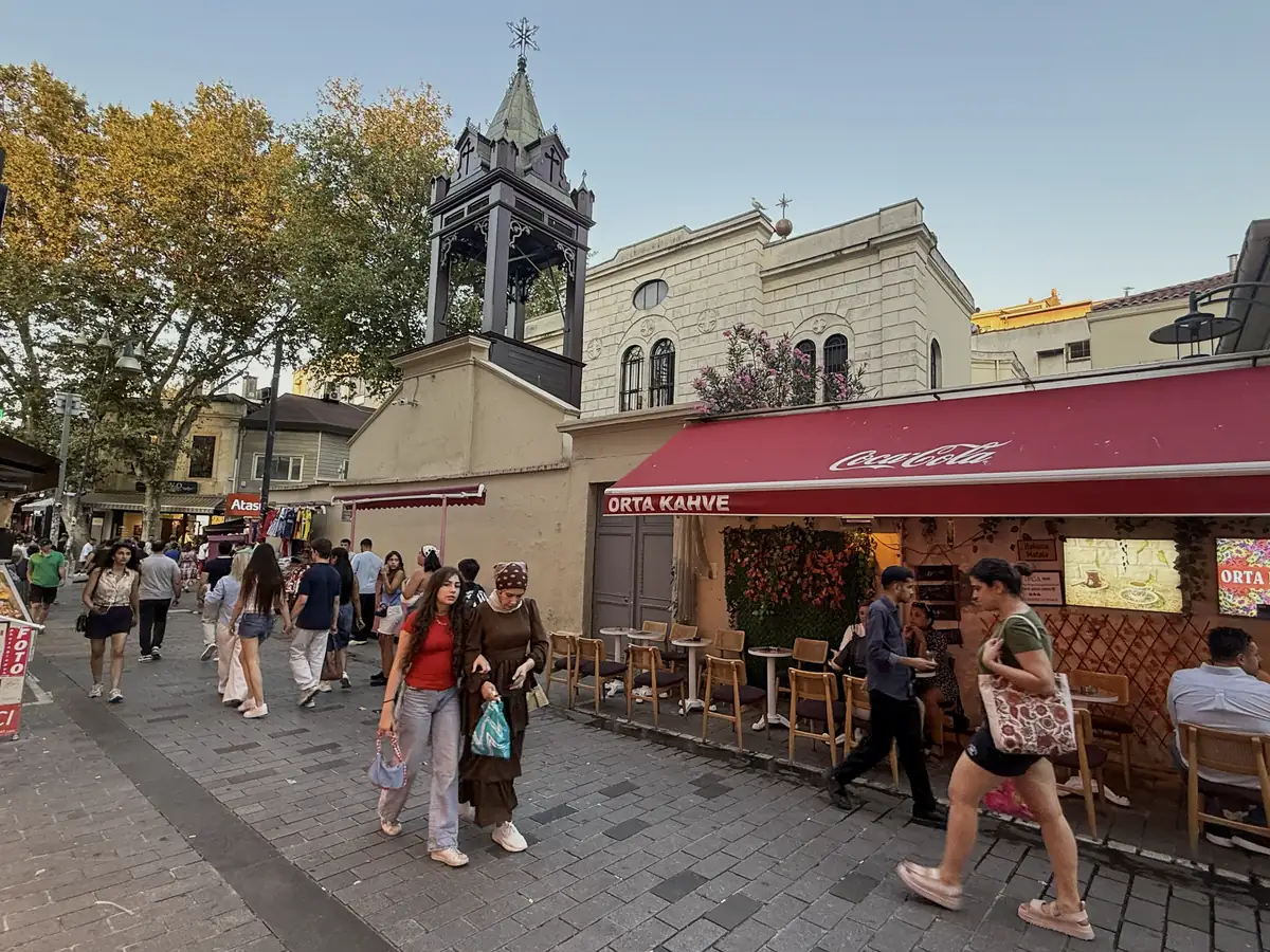 Bell tower of Surp Takavor Armenian Church rising over a busy café street in Kadıköy Market