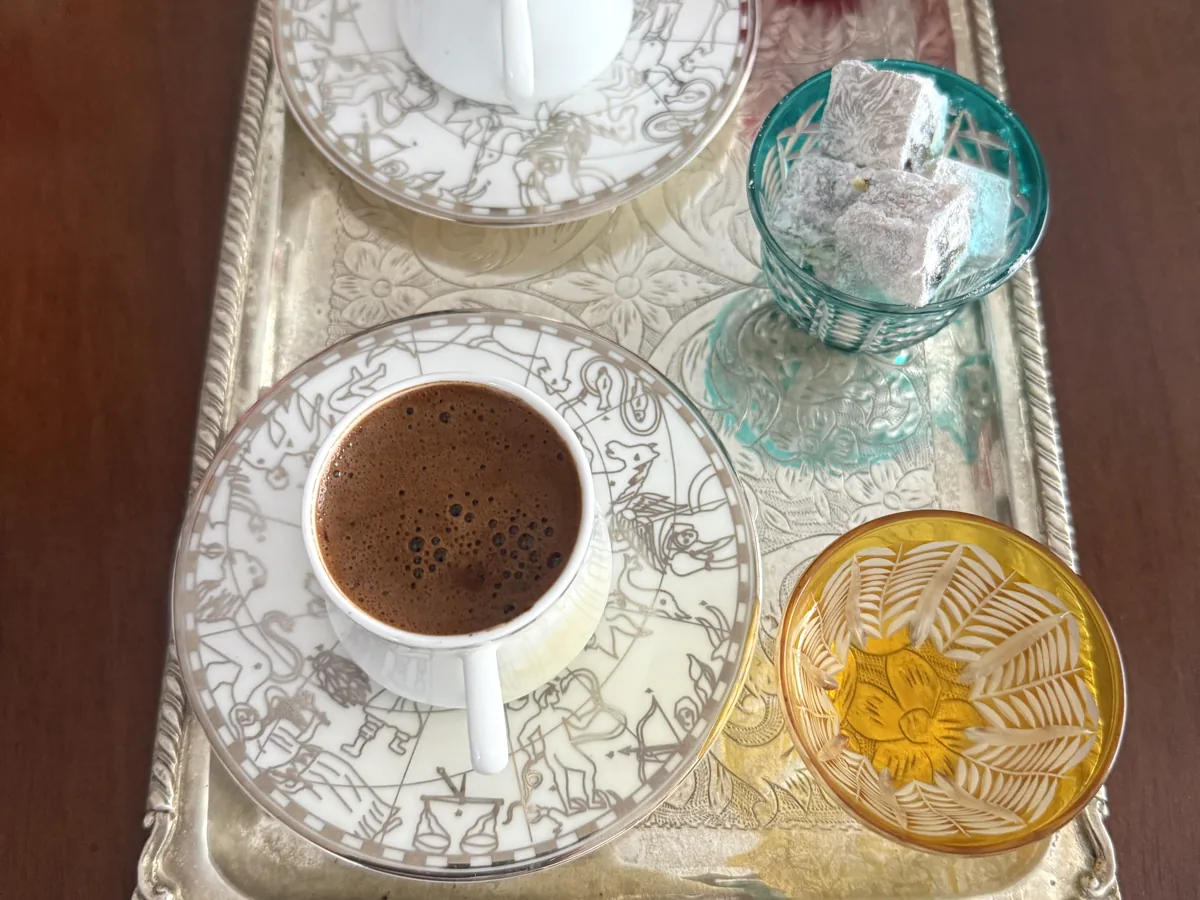 Overhead view of Turkish coffee in a porcelain cup on a silver tray, with Turkish delight in coloured glass bowls