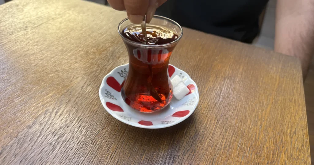 Turkish drinks: what to drink in Turkey — a glass of Turkish tea being stirred in Kadıköy, Istanbul