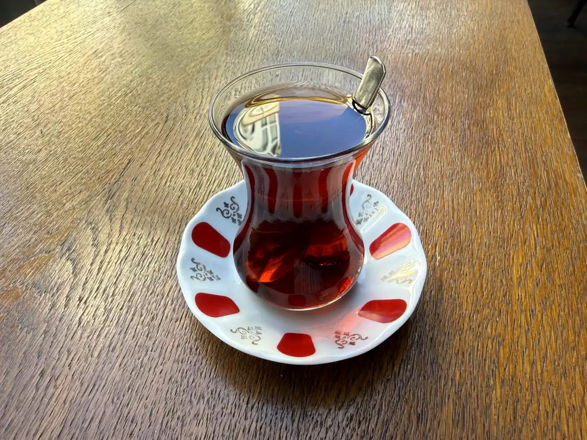 A tulip-shaped glass of ruby-red Turkish tea (çay) on a red-patterned saucer at a Kadıköy café